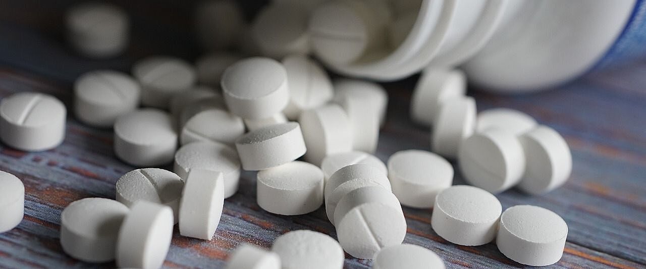 Weiße Tabletten, die aus einer Verpackung herauskullern